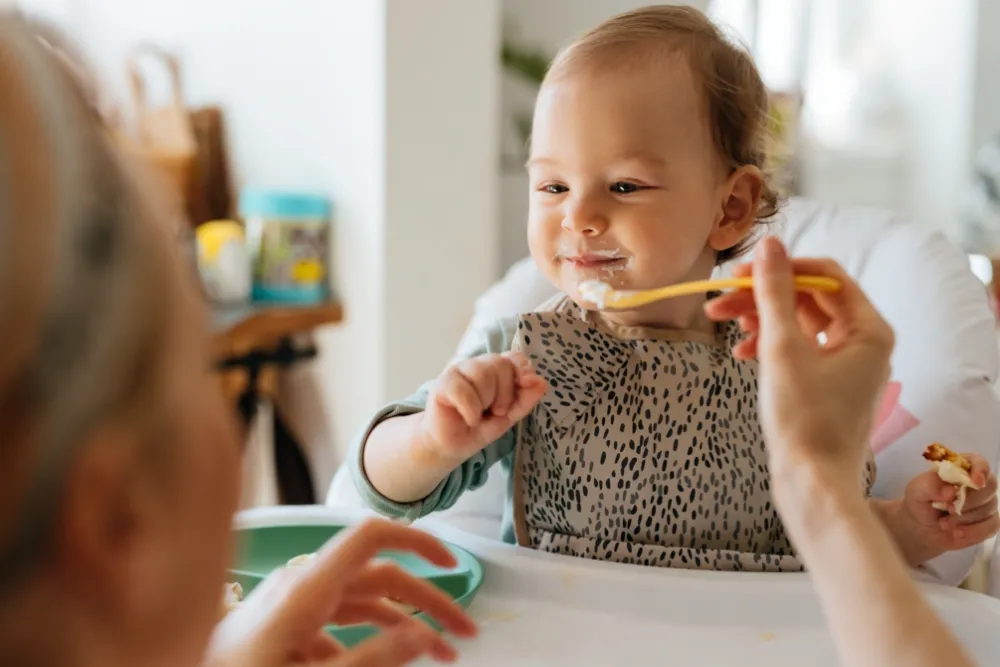 Person gently feeding a baby with a spoon