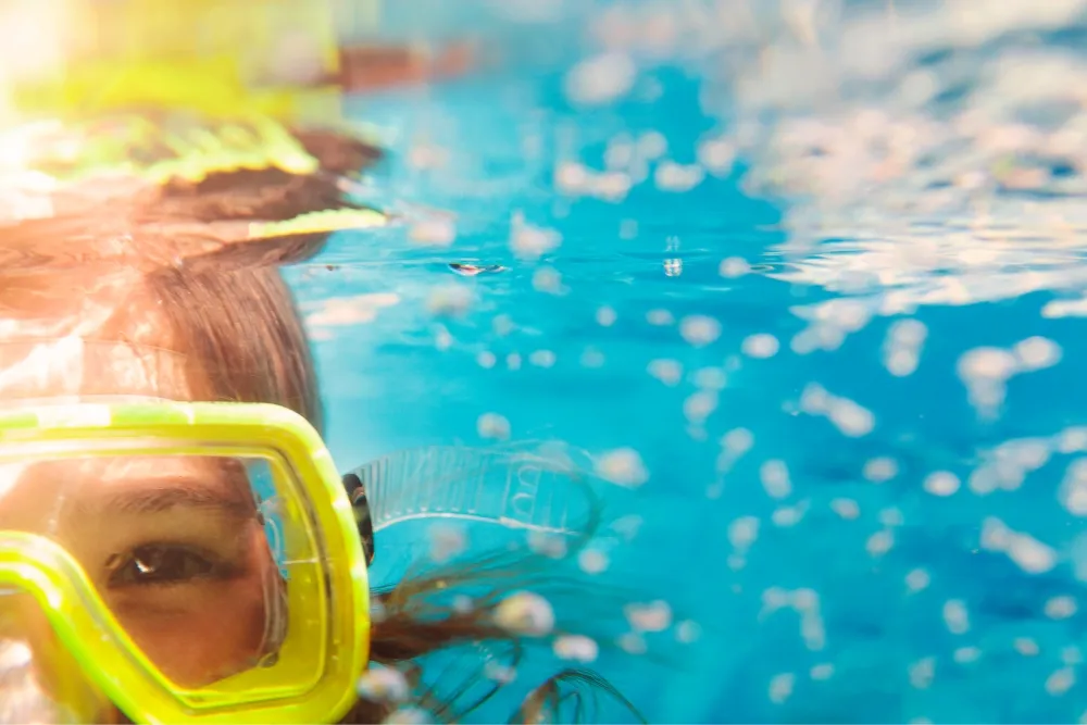Child wearing a diving mask looking at the camera